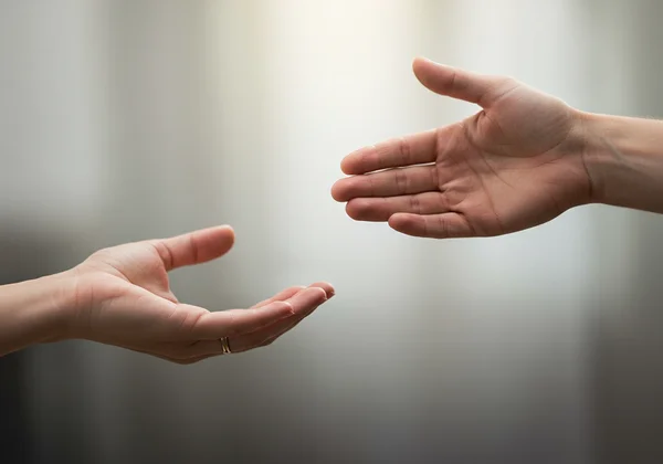 A person reaching out a hesitant hand towards a welcoming, open hand
