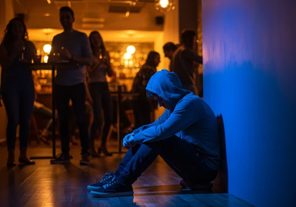 Person isolated, avoiding social interaction due to fear of rejection.